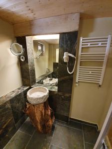 un baño con lavabo y un tronco de madera. en Alpin Lodge en Azuga