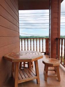 una mesa de madera y un banco en un balcón con vistas en คอมคิม ริมโขง เชียงคาน, en Loei