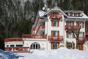 a large white house with red balconies in the snow at Chalet Hôtel La Sapinière in Chamonix-Mont-Blanc