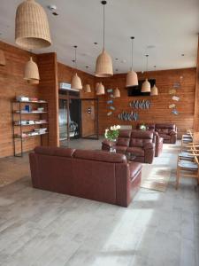 - un salon avec des meubles en cuir brun et des lampes suspendues dans l'établissement Hotel Boutique Puramar, à Curanipe