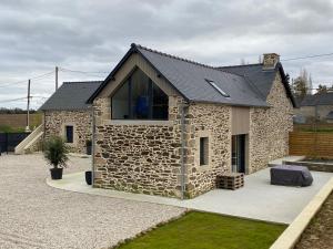 een stenen huis met een zwart dak bij LA GIENDROTAIS in Corseul