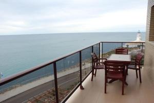 a balcony with a table and chairs and the ocean at Aparthotel El Faro in Cullera