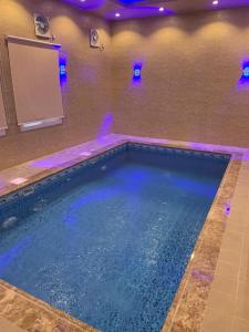 una gran piscina con luces azules en una habitación en منتجع حديقة الوسام en Taif