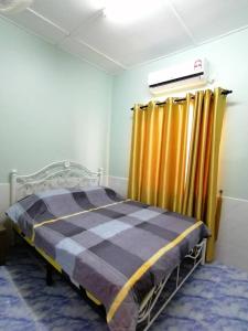 a bedroom with a bed and yellow curtains at Mui Gim Homestay 大港 美景民宿 in Sungai Besar