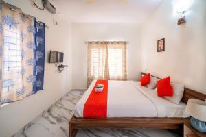 een slaapkamer met een bed met rode kussens en een raam bij Sports Icon Suites in Yelahanka