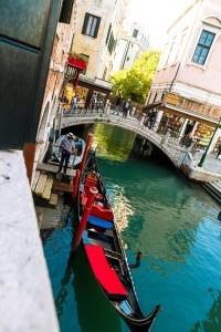 una barca è ormeggiata in un canale con un ponte di Hotel Al Vagon a Venezia