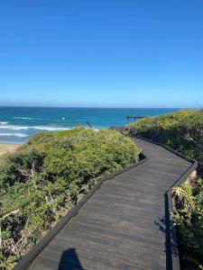 un chemin en bois menant à l'océan sur une plage dans l'établissement Relax & Recharge, à Boggomsbaai