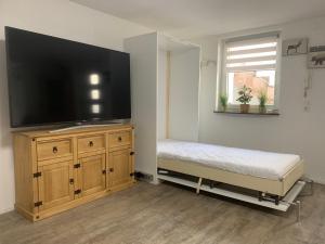 a bedroom with a large flat screen tv on a wooden cabinet at GOLDSTADT LOUNGE in Pforzheim