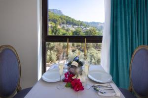 a table with plates and flowers on it with a window at Highclere Hotel and Spa in Faralya