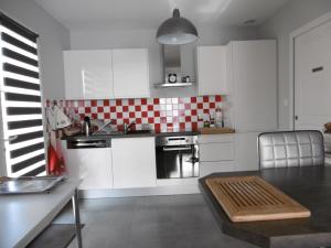 a kitchen with white cabinets and red and white tiles at Maison d'Hôtes La Marie Pierre in Pluherlin