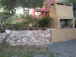 a stone wall next to a building with a fireplace at Los Frutales in Villa Carlos Paz