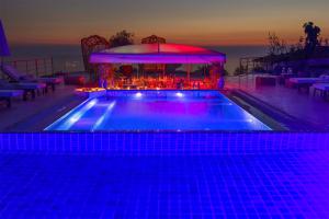 a swimming pool with a bar in the background at night at Highclere Hotel and Spa in Faralya