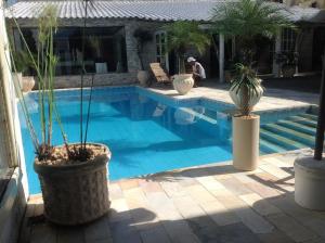 a swimming pool with potted plants next to a house at Perohouse in Cabo Frio