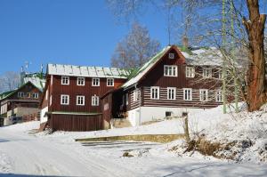 a large wooden barn with snow on the ground at Hotel Peklo pro rodiny s dětmi in Josefŭv Dŭl
