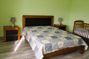 a bedroom with a bed and two night stands and a crib at Casa dos cinco sentidos in Feteira Pequena