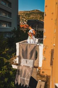 a woman standing on a balcony with an umbrella at Apartman Balkon in Mostar