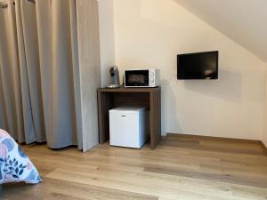 een kamer met een kleine koelkast en een tv aan de muur bij LA GIENDROTAIS in Corseul
