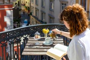 a woman sitting at a table on a balcony with a book at Petros Hotel in Istanbul