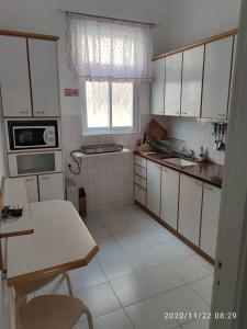 a kitchen with white cabinets and a table and a window at Apartments COMFY - for a quiet family holiday in Haifa