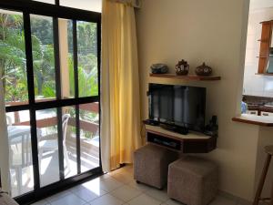 a living room with a flat screen tv next to a sliding glass door at Riviera Green in Riviera de São Lourenço