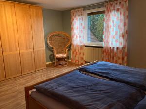 ein Schlafzimmer mit einem Bett, einem Stuhl und einem Fenster in der Unterkunft Ferienwohnung auf dem Land und trotzdem stadtnah. in Herford