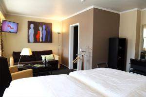a bedroom with a white bed and a living room at Hotel Altstadt-Passage in Wittingen