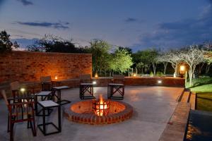 a patio with a fire pit and tables and chairs at Ngala Lodge in Klipdrift