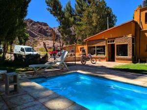 una piscina con una silla, una mesa y una casa en Hosteria Uspallata en Uspallata