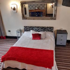 The Saracens Head Old Lounge في سكيجنيس: غرفة نوم بسرير وبطانية حمراء ومرآة