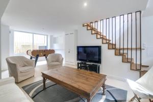 a living room with a wooden table and a staircase at MAISON MODERNE ET SPACIEUSE AU CENTRE DE DEAUVILLE in Deauville