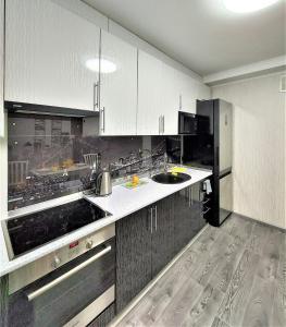 a kitchen with white cabinets and a black refrigerator at Атмосферная 1-к квартира м Левобережная in Kyiv