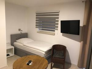 Kleines Zimmer mit einem Bett, einem Tisch und einem TV. in der Unterkunft Hotel Zum Weinberg in Cremlingen