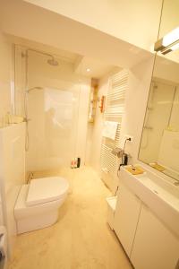 a white bathroom with a toilet and a sink at Hoheschule Apartment Kapriole in Vienna