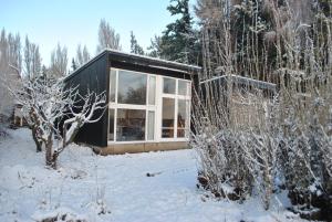 una casa negra en la nieve con árboles en Hostería de la Patagonia, en Chile Chico