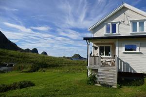 Casa blanca con porche en un campo verde en Koselig Hytte mellom sjø og fjell, en Nykvåg