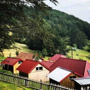 a group of barns with red roofs next to a fence at Katun Lanista-Kolibe Bogavac in Mojkovac