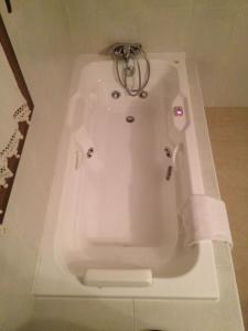 una bañera blanca con una toalla encima en Hotel Las Fuentes, en Torrecaballeros
