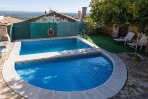 a large blue swimming pool in a yard at Hotel Palacio Guzmanes in Baños de la Encina