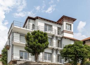 biały budynek z balkonami i drzewami w obiekcie Villa Simonetta w mieście Bee