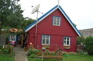 una casa roja con techo azul en un patio en Inkaro Kaimas en Nida