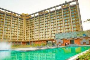 a large hotel with a swimming pool in front of it at Studio Stays in Surat
