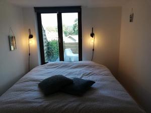 una camera da letto con un letto con due cuscini e una finestra di Appartement cosy Spa a Spa
