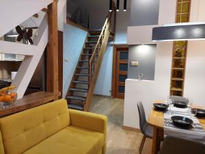 a living room with a yellow couch and a staircase at Copernicus 10 in Olsztyn