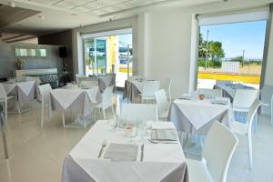 a restaurant with white tables and white chairs and windows at Villa Imago in Roseto degli Abruzzi
