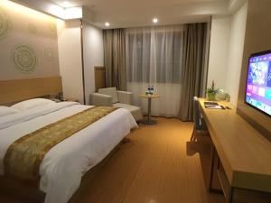 a hotel room with a large bed and a flat screen tv at GreenTree Inn Shaoxing Binhai New City Dongsen Commercial Square Hotel in Shaoxing