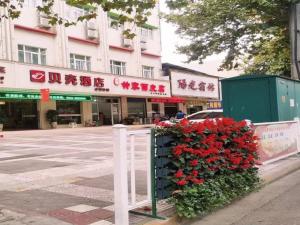 un arbusto con flores rojas delante de un edificio en Shells Hanzhong City High Railway Station Renmin Road Hotel, en Hanzhong