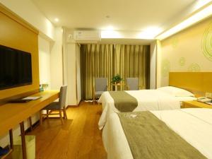 a hotel room with two beds and a desk and a television at GreenTree Inn Shangqiu Liangyuan District Suiyang Avenue Hotel in Shangqiu