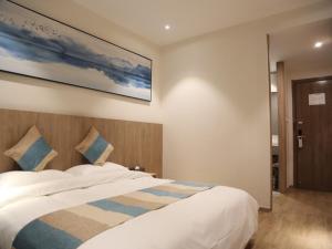 a bedroom with a bed with a painting on the wall at VX Zibo Zhangdian District Jinjing Avenue Hotel in Zibo