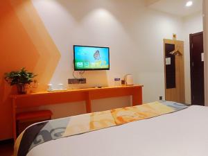 a bedroom with a bed and a television on a desk at Shell Tai'an Taishan District Xinhuacheng International Plaza Hotel in Tai'an