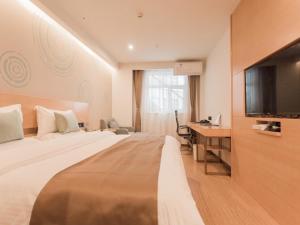 ein Hotelzimmer mit einem Bett, einem Schreibtisch und einem TV in der Unterkunft GreenTree InnZhangjiakou High-speed Railway Station Business Hotel in Zhangjiakou